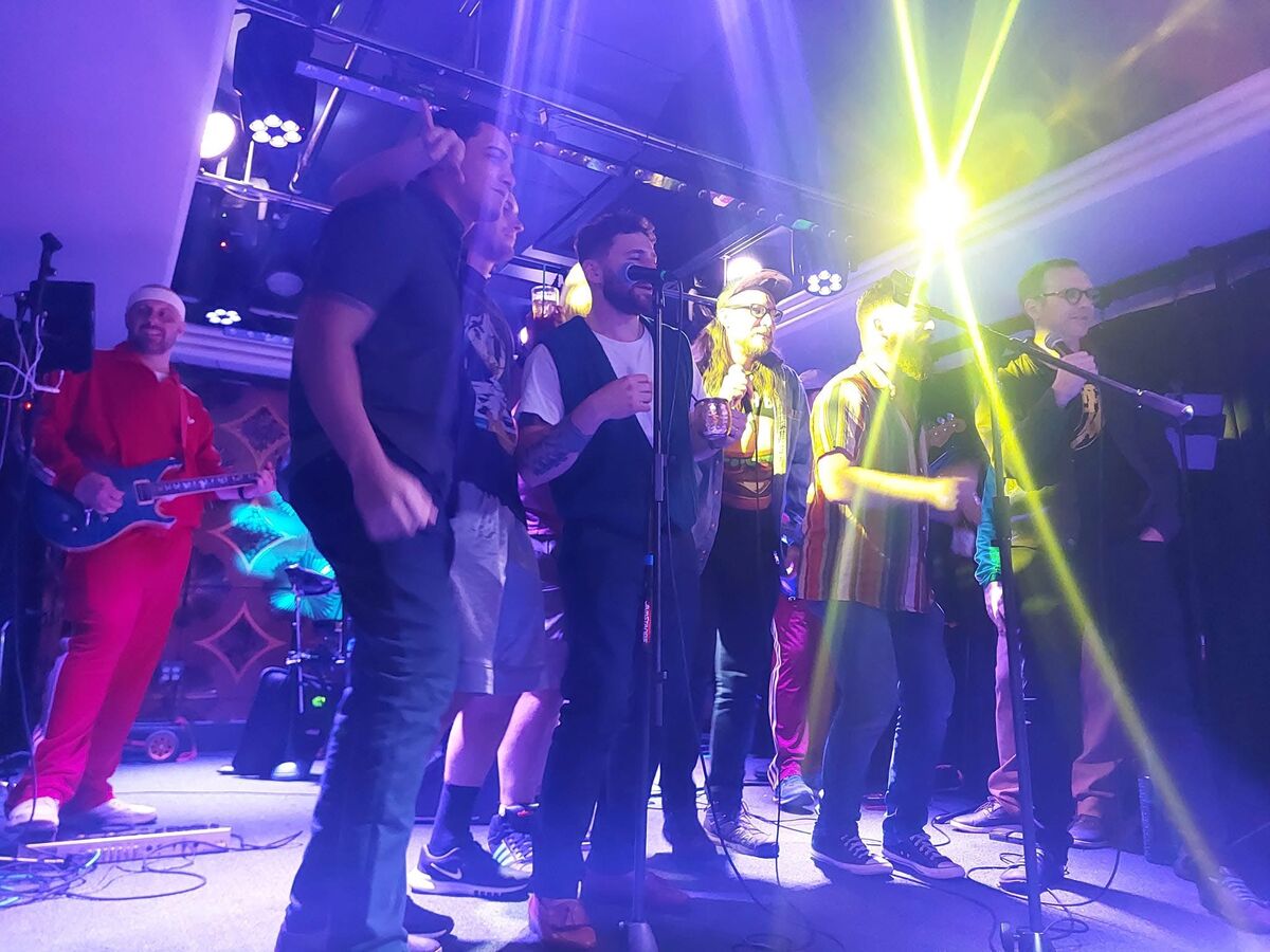 Packed stage group singalong with dramatic blue and purple lighting at a Pittsburgh music venue